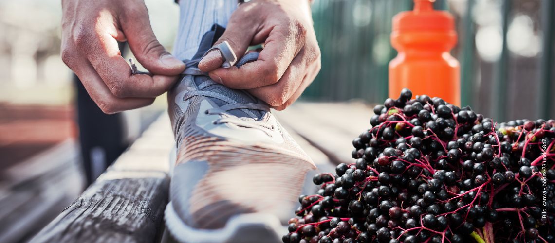 Jemand bindet seinen Sportschuh, orange Trinkflasche im Hintergrund und Holunderbeeren vorne zum Thema Holunder als Nahrungsergänzung im Sport